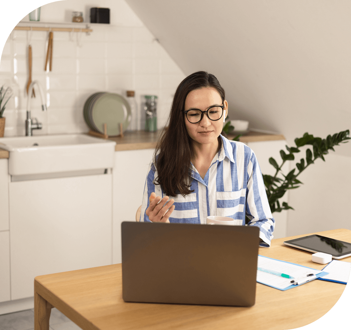 Woman working on laptop in kitchen.