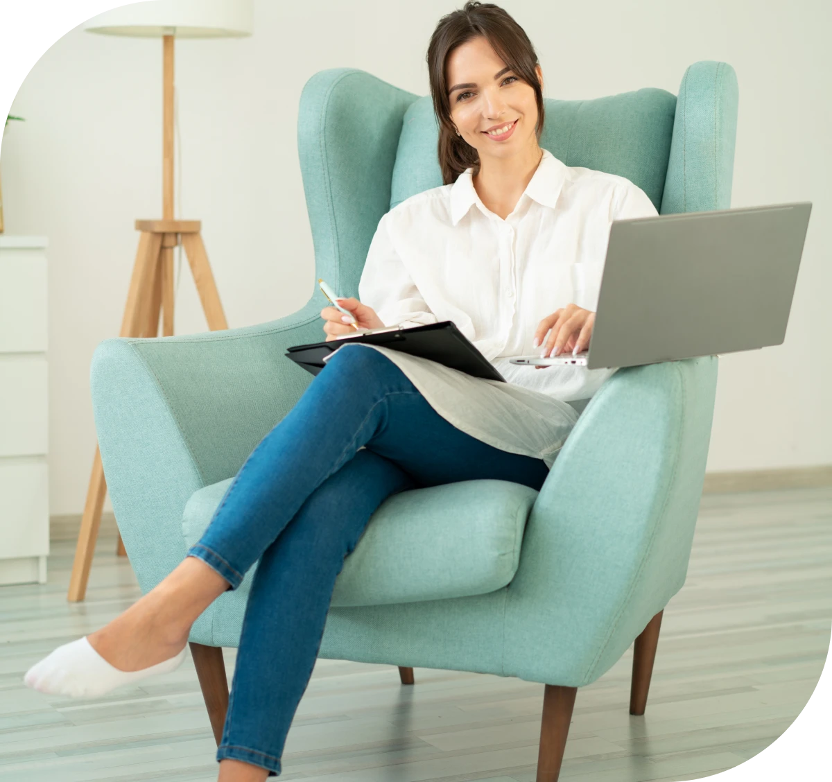 Woman smiling, sitting with laptop and notebook.
